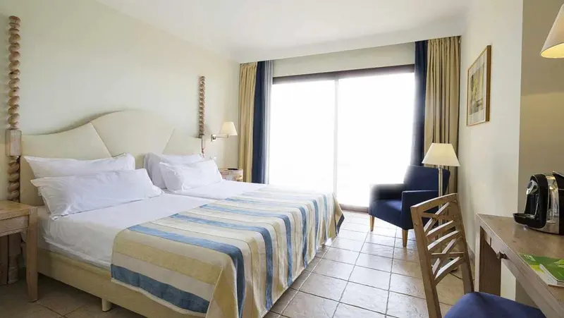 Une chambre lumineuse avec un grand lit et un coin salon.