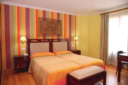 Une chambre lumineuse avec deux lits et un décor mural coloré.