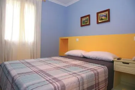 Une chambre lumineuse avec un lit recouvert d'une courtepointe à carreaux.