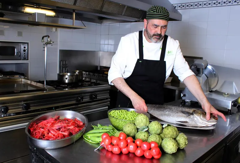 Un chef de cuisine prépare un poisson frais avec des légumes.