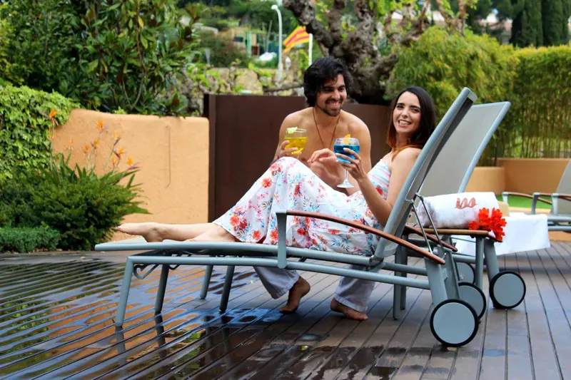 Un couple se détend sur des transats au bord d'une piscine.