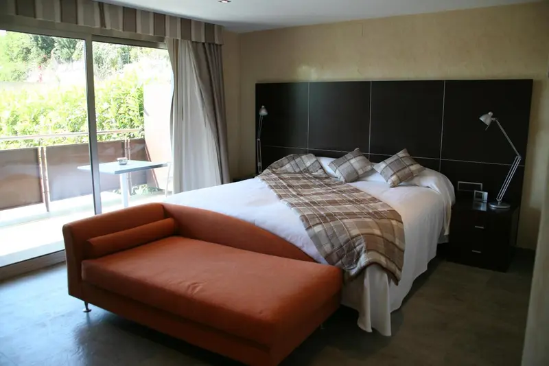 Une chambre lumineuse avec un grand lit et un coin salon donnant sur une terrasse.