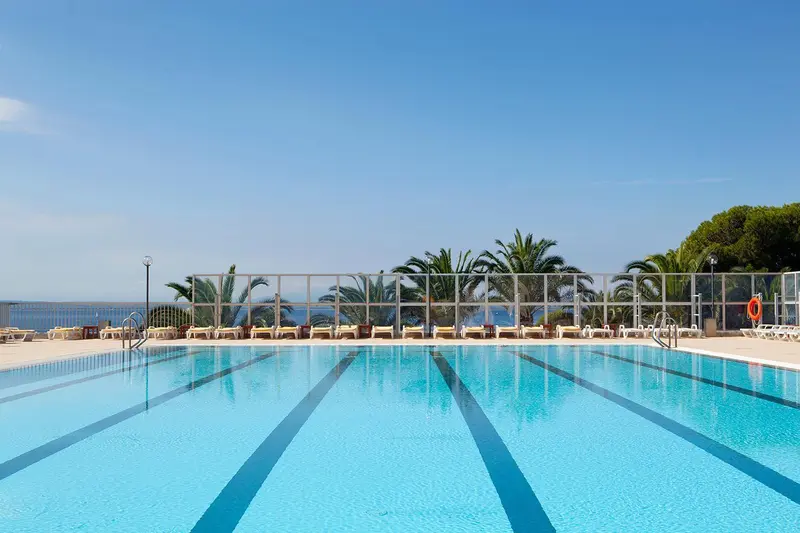 Une piscine rectangulaire avec des lignes bleues et des transats alignés au bord.