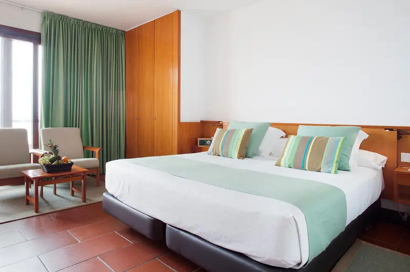 Une chambre lumineuse avec un lit double et un coin salon.