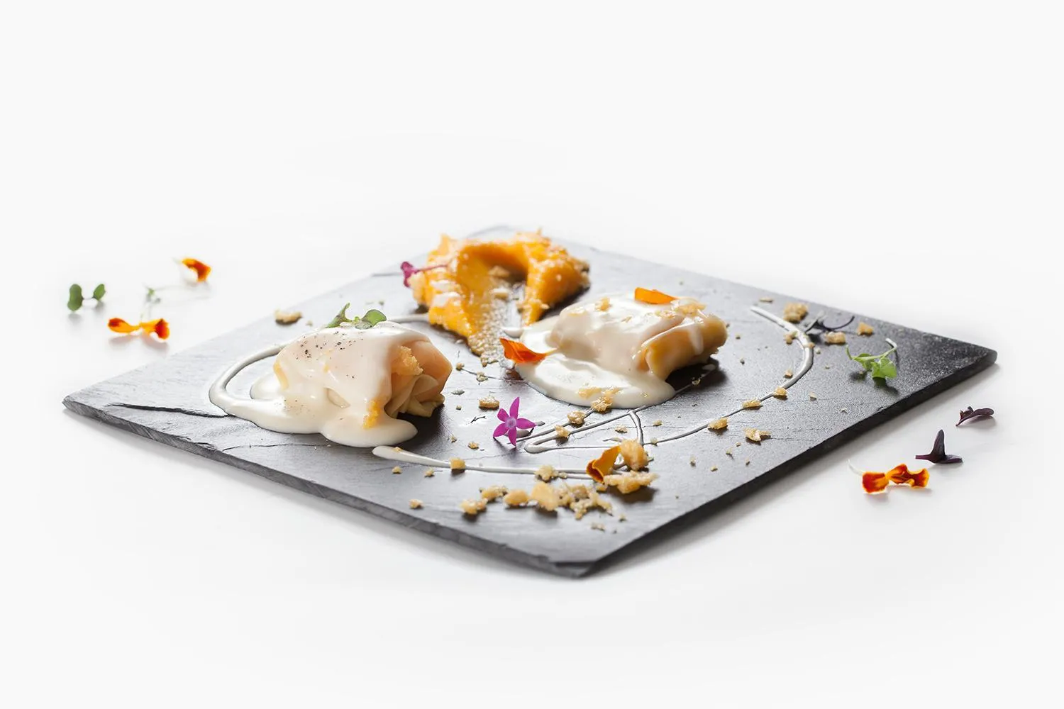 Assiette raffinée avec des éléments culinaires disposés sur une ardoise noire.