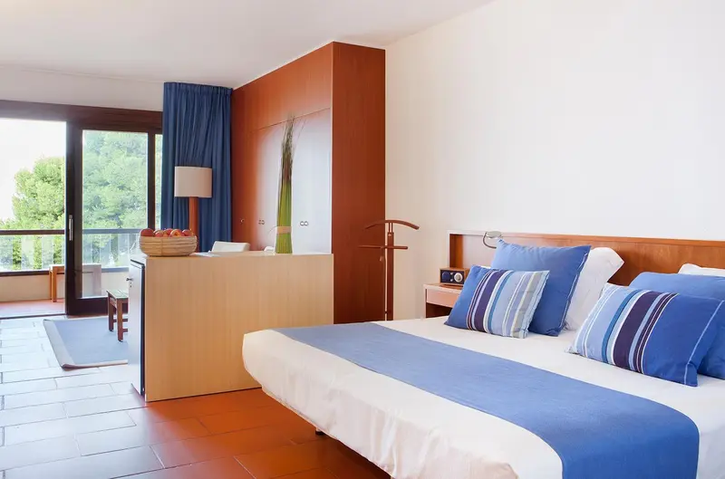 Chambre lumineuse avec un grand lit et une terrasse.