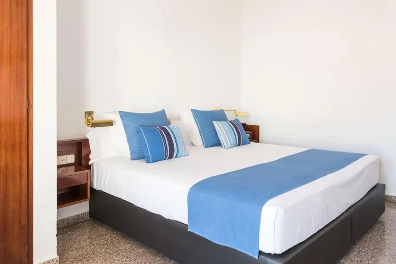 Une chambre lumineuse avec un grand lit recouvert d'une courtepointe bleue.