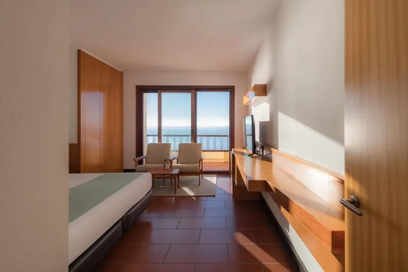 Une chambre lumineuse avec un coin salon et vue sur la mer.