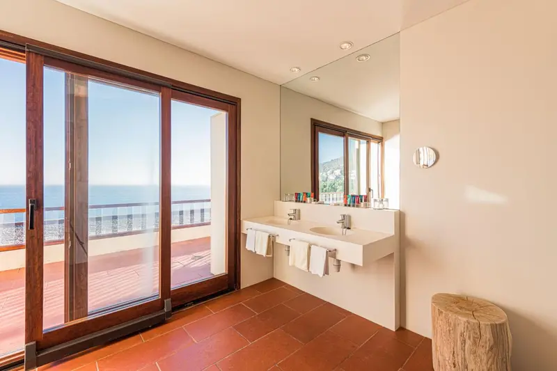 Une salle de bain lumineuse avec double vasque et vue sur la mer.