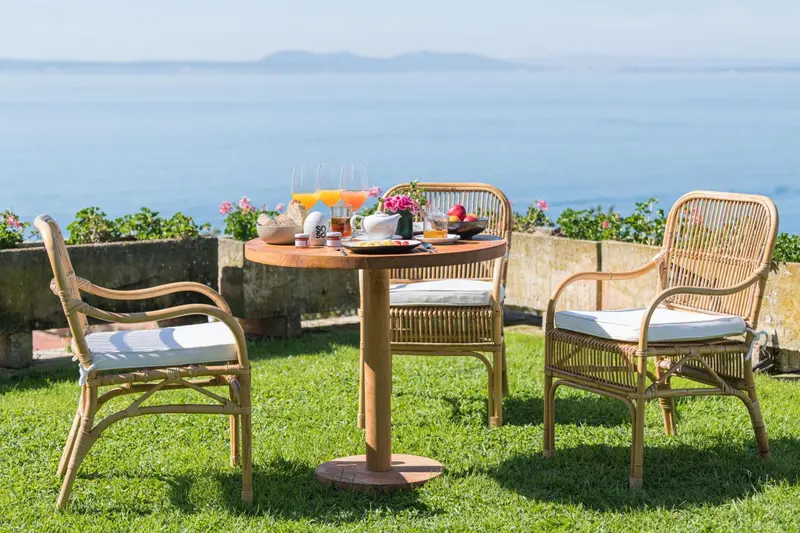 Table de petit-déjeuner dressée sur une terrasse avec vue sur la mer.