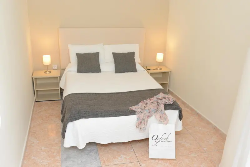 Une chambre lumineuse avec un grand lit recouvert d'une couverture et de coussins.