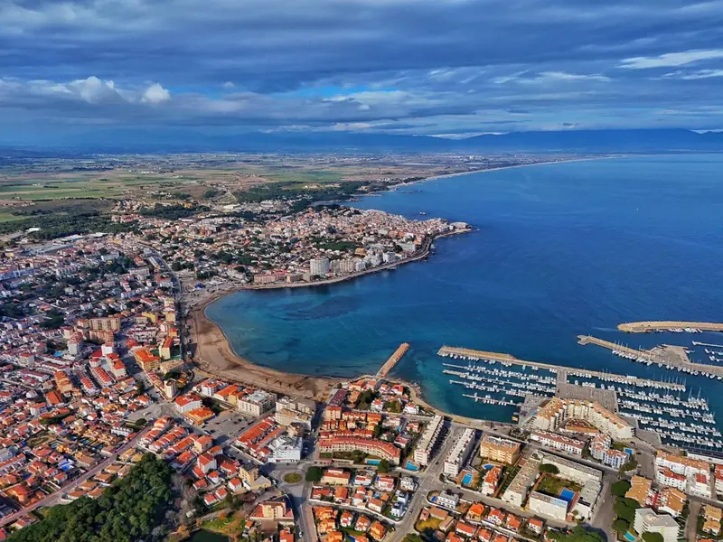 Vue aérienne d'une ville côtière avec une plage et un port de plaisance.