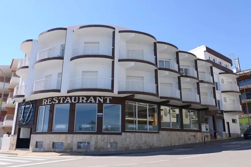Façade d'un bâtiment blanc avec des balcons et un restaurant au rez-de-chaussée.