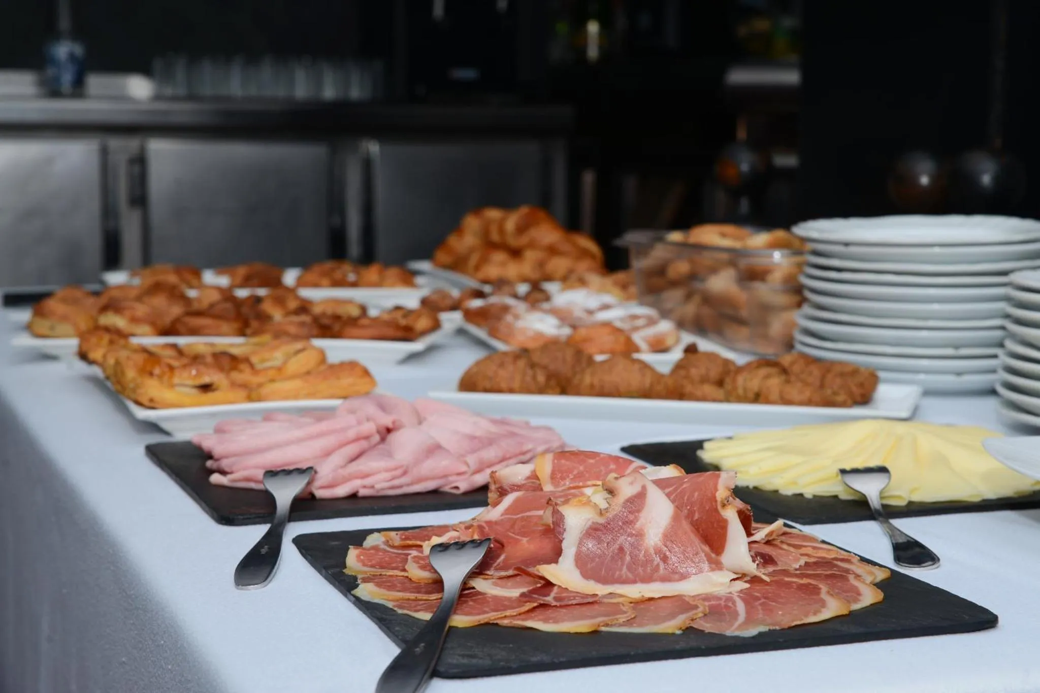 Une table garnie de viennoiseries, de charcuterie et de fromage.