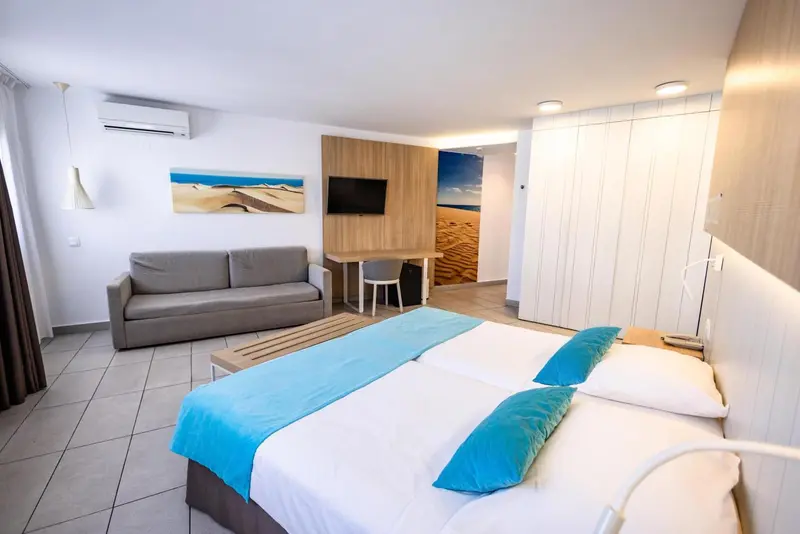 Une chambre lumineuse avec un canapé, un lit et un téléviseur mural.