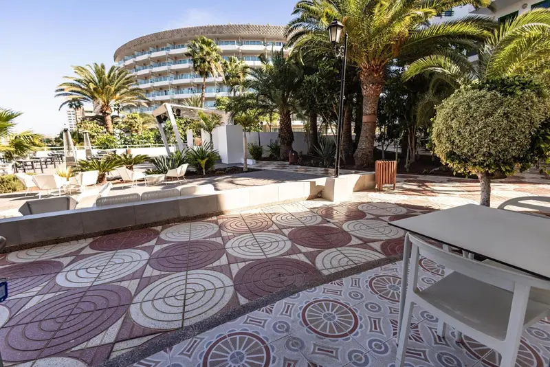Allée pavée mène vers un bâtiment blanc entouré de végétation tropicale.