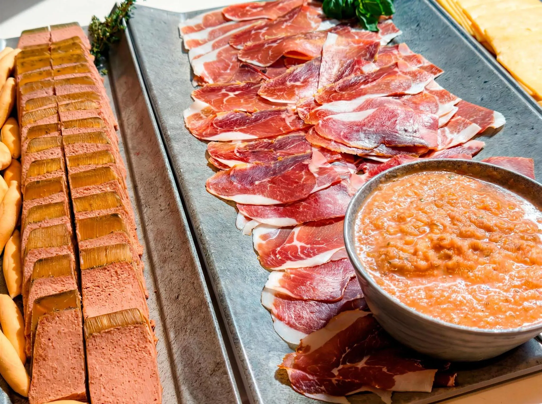 Assortiment de charcuteries et de fromage servis avec une sauce.