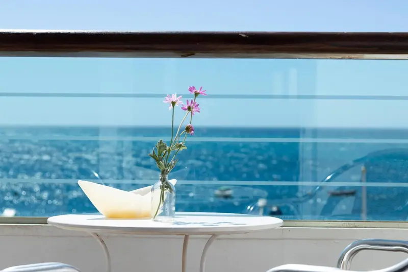 Une table blanche avec une petite composition florale face à la mer.