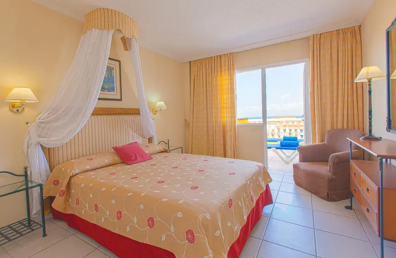 Chambre lumineuse avec un lit à baldaquin et vue sur la mer.