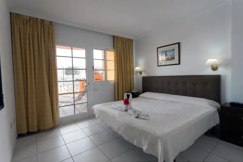 Une chambre lumineuse avec un grand lit et un accès à une terrasse.
