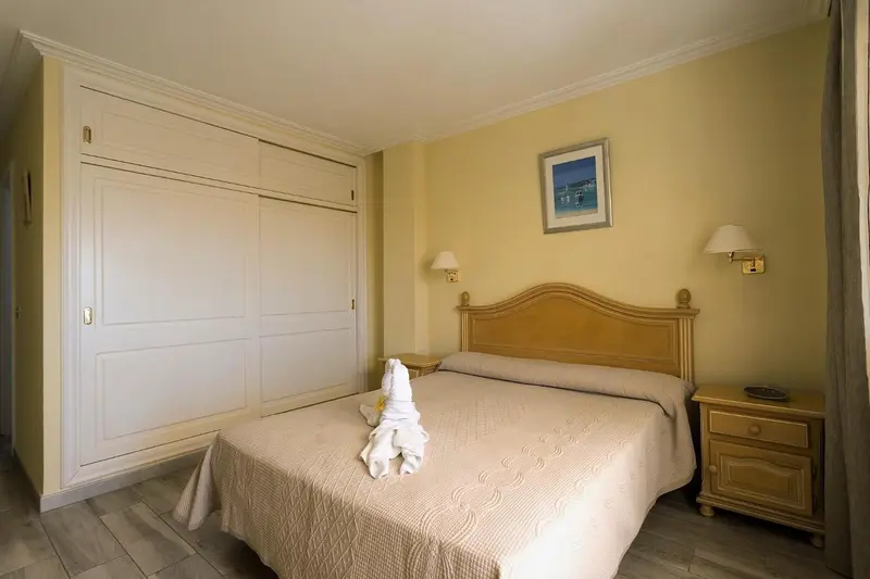 Une chambre lumineuse avec un grand lit et une armoire.