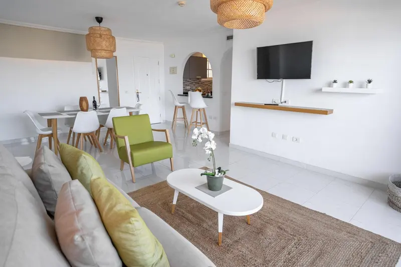 Espace de vie lumineux avec canapé, fauteuil et table à manger.
