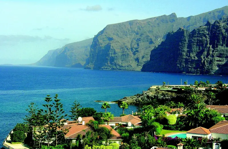Vue d'une côte rocheuse avec des bâtiments et une végétation luxuriante.