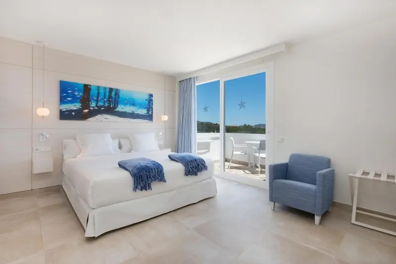 Chambre lumineuse avec un grand lit et un accès à une terrasse.