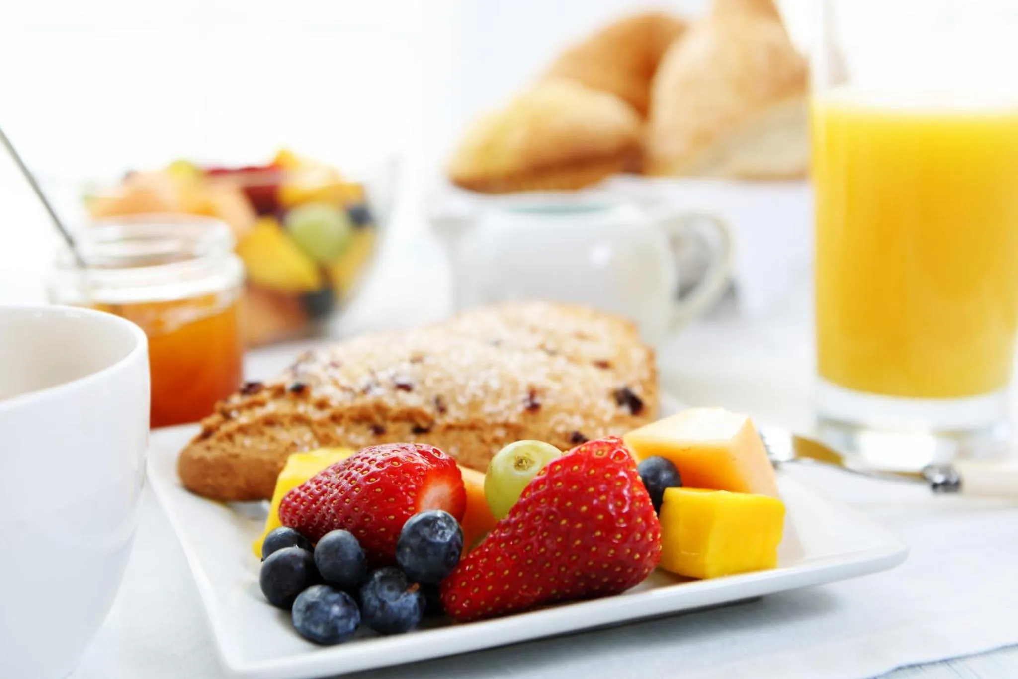 Une table est dressée avec des viennoiseries, des fruits frais et des jus.