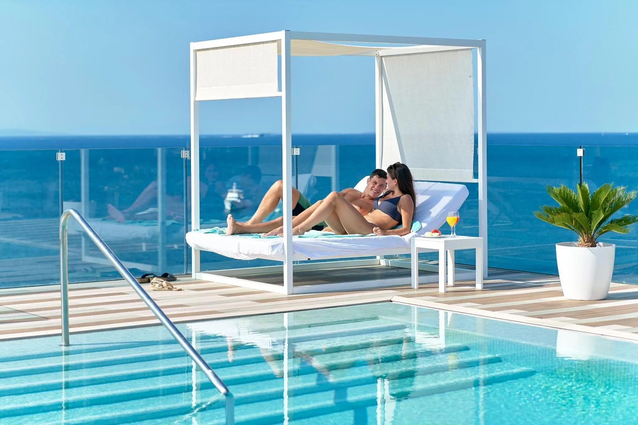 Couple se relaxant sur des transats au bord d'une piscine avec vue sur la mer.