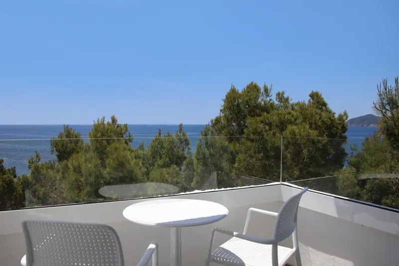 Terrasse avec mobilier blanc donnant sur la mer et la végétation.