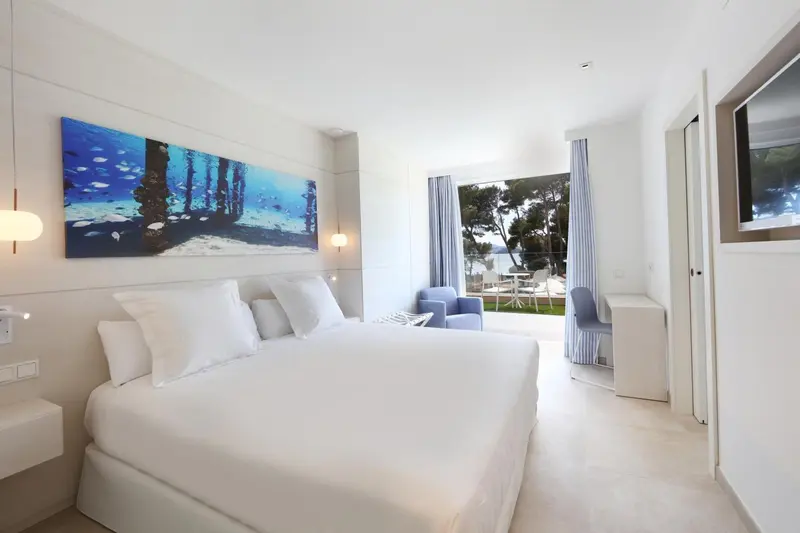 Chambre lumineuse avec un grand lit et une vue sur la mer.