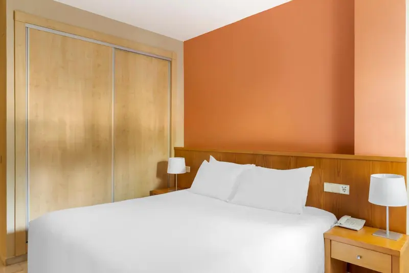 Une chambre lumineuse avec un grand lit blanc et des meubles en bois.