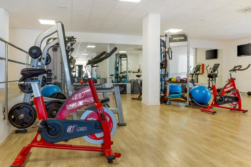 Une salle de sport lumineuse avec des équipements de musculation et des vélos d'appartement.