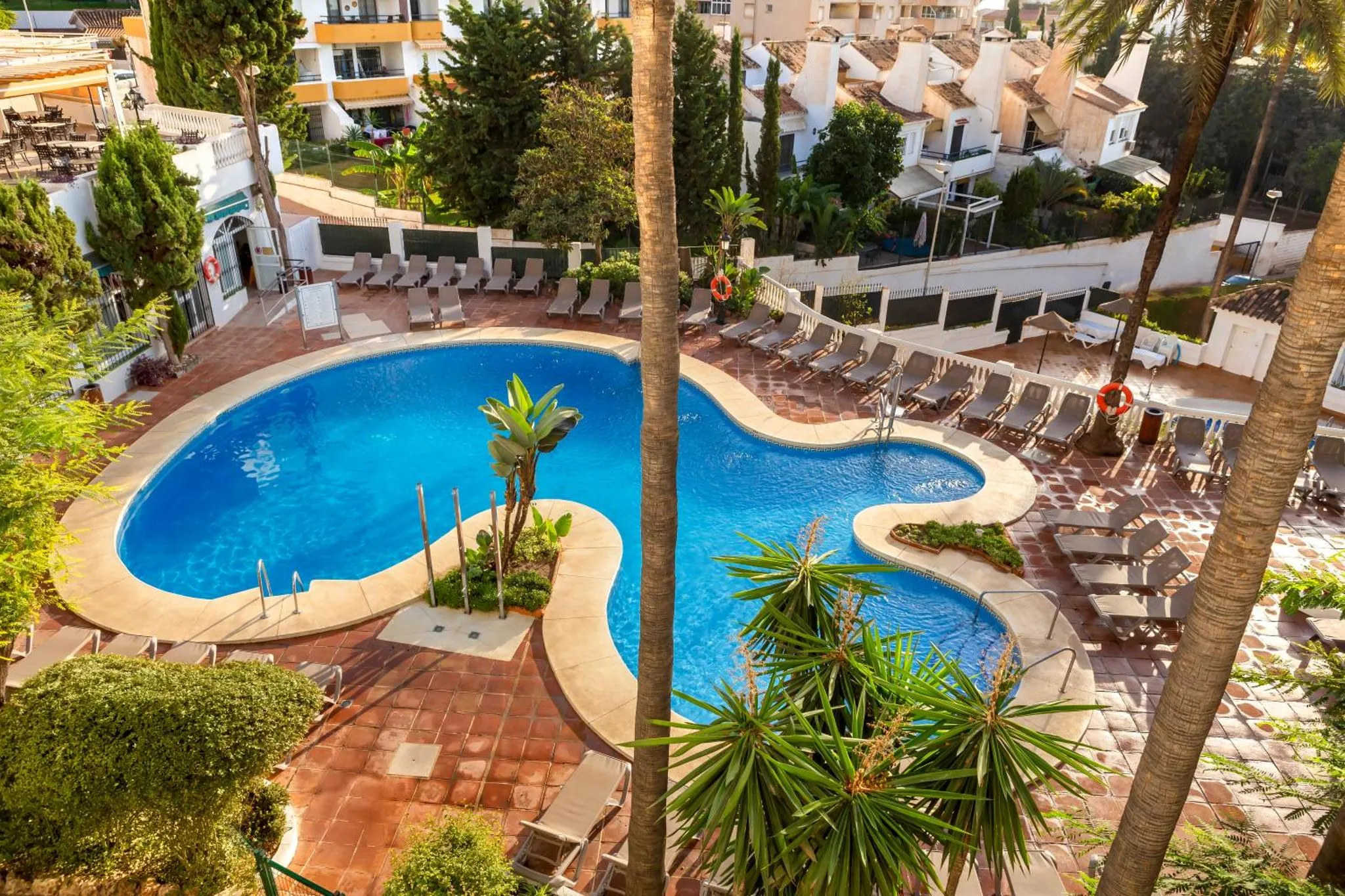 Deux piscines extérieures avec transats et végétation tropicale.