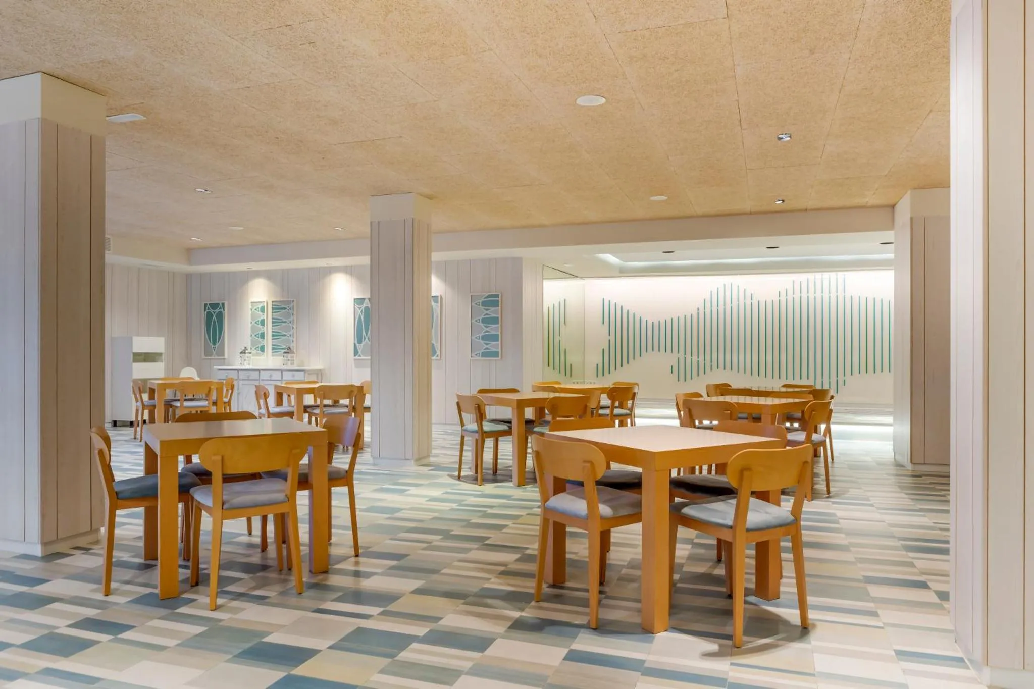 Une salle lumineuse avec des tables et des chaises disposées sur un sol à motifs.