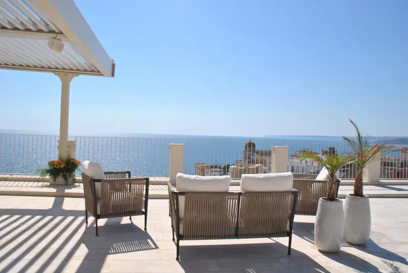 Mobilier d'extérieur sur une terrasse avec vue sur la mer et la côte.