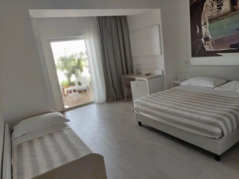 Une chambre lumineuse avec un lit et un bureau près d'une baie vitrée.