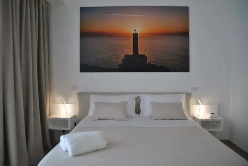 Une chambre lumineuse avec un grand tableau représentant un phare au coucher du soleil.