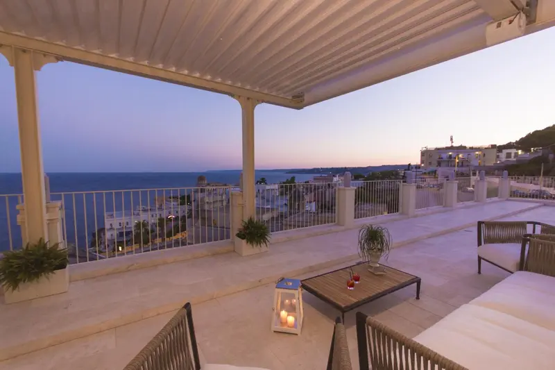 Terrasse avec mobilier d'extérieur et vue sur la mer au crépuscule.