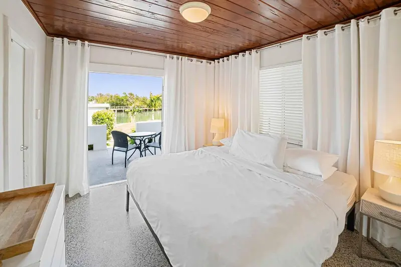 Une chambre lumineuse s'ouvre sur une terrasse avec mobilier de jardin.