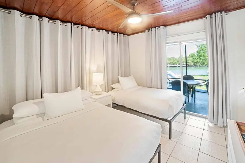 Chambre lumineuse avec deux lits simples et vue sur un jardin.