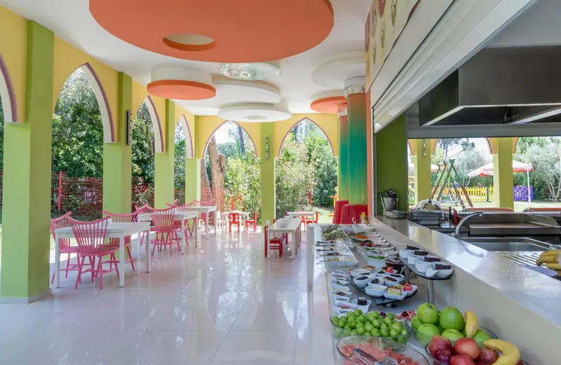 Un buffet propose des fruits frais et des pâtisseries dans un espace lumineux et coloré.