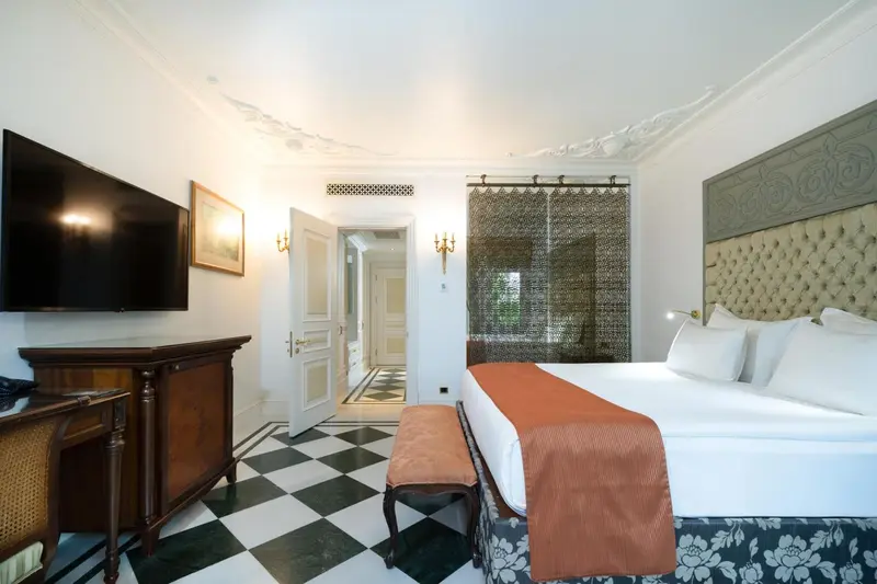 Une chambre spacieuse avec un grand lit et un parquet à carreaux.