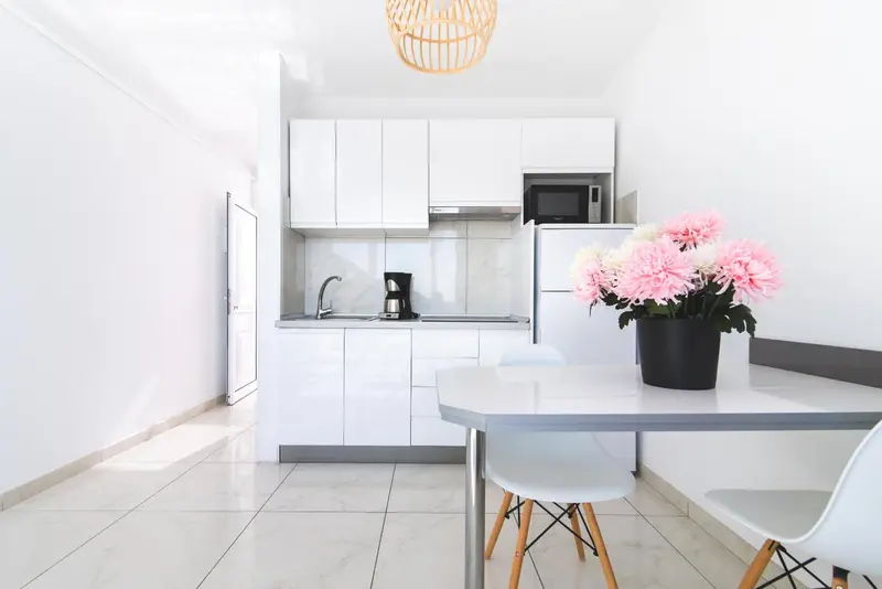 Une cuisine blanche lumineuse avec une table et des chaises.