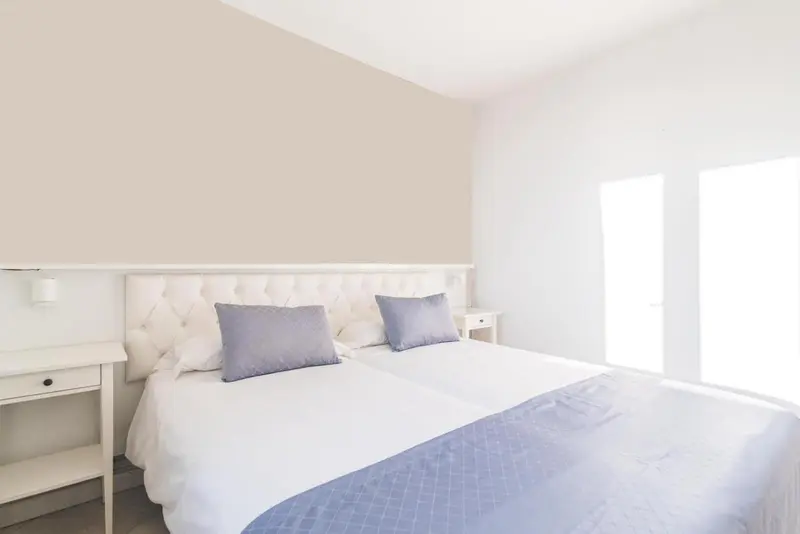 Une chambre lumineuse avec un grand lit recouvert d'une courtepointe blanche et bleue.