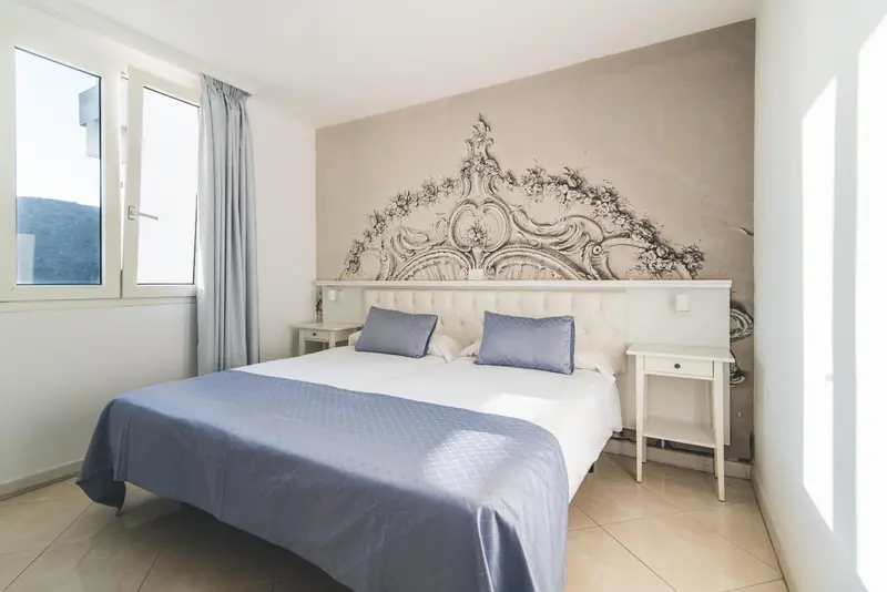 Une chambre lumineuse avec un grand lit et une décoration murale ornementale.