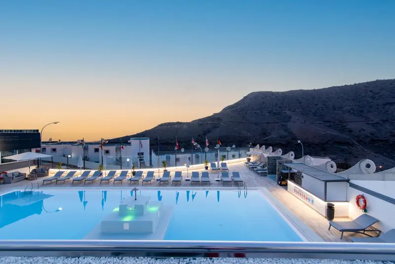 Terrasse avec piscine et vue sur les collines au coucher du soleil.