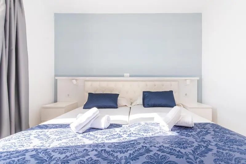 Une chambre lumineuse avec un grand lit recouvert d'une courtepointe bleue et de deux oreillers.