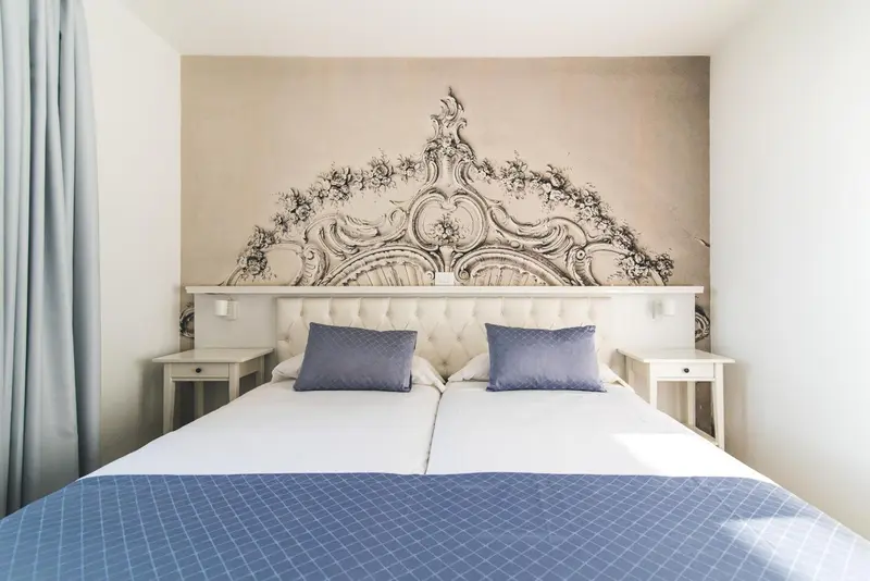 Une chambre lumineuse avec un grand lit et une décoration murale ornementale.